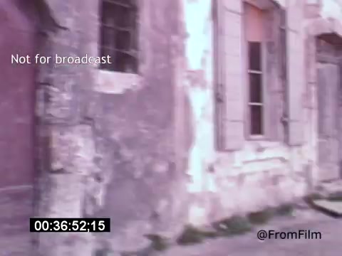 The still from *Vincent Van Gogh: A Self-Portrait (1961)* features an aged, textured wall of a building, hinting at a historic or rural setting. The faded colors evoke a sense of nostalgia, emphasizing the film's introspective and artistic themes. The presence of windows, some partially open, adds depth and a hint of mystery to the scene.