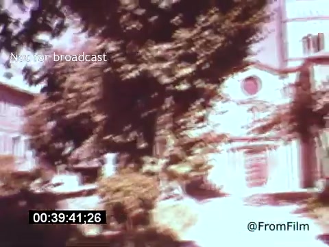 The still from 'Vincent Van Gogh: A Self-Portrait' (1961) captures a scene filled with lush greenery and a historical building, likely representative of the environments that influenced Van Gogh's work. The colors appear vibrant yet slightly washed out, typical of 16mm film. The framing suggests a tranquil outdoor setting, possibly connecting to themes of nature that permeate Van Gogh's art. The presence of light and shadow hints at the dynamic emotional landscapes found in his paintings.