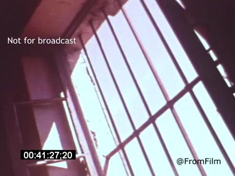 The still from 'Vincent Van Gogh: A Self-Portrait (1961)' features a view through barred windows, suggesting confinement and isolation. The colors are likely soft and muted, typical of the film's palette, evoking the emotional depth of Van Gogh's life and struggles. This moment may symbolize the artist's turbulent state of mind, emphasizing themes of despair intertwined with creativity.