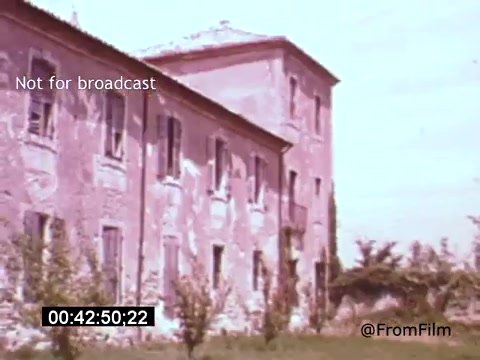 The still from *Vincent Van Gogh: A Self-Portrait* (1961) features an exterior view of a weathered building surrounded by vegetation, likely associated with Van Gogh's time. The faded colors and textures suggest a historical context, reflecting the somber yet poignant themes often present in the film, narrated by Lee J. Cobb. The shot captures a sense of solitude and introspection, aligning with Van Gogh's artistic journey.