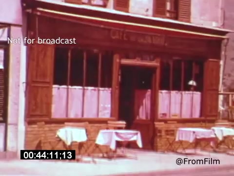 The still from 'Vincent Van Gogh: A Self-Portrait' (1961) depicts a quaint café exterior, characterized by wooden structures and inviting details. Tables are set outside, likely intended for patrons to enjoy the atmosphere. The scene is imbued with a warm, nostalgic color palette, enhancing the artistic theme of the film, which features Lee J. Cobb's portrayal. The image captures a moment of everyday life, reflecting Van Gogh's connection to the settings that inspired his work.