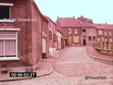 The still from 'Vincent Van Gogh: A Self-Portrait' (1961) depicts a quiet, cobblestone street lined with rustic buildings. The scene conveys a sense of tranquility, emphasizing the artistic and historical context of Van Gogh’s life. The muted colors and vintage film quality enhance the nostalgic atmosphere, suggesting a connection to the artist’s environment. The presence of Lee J. Cobb suggests a narration or dramatic element, adding depth to the visual narrative.