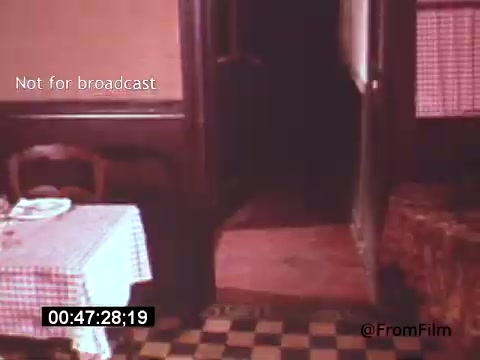 The still from 'Vincent Van Gogh: A Self-Portrait' (1961) features a dimly lit interior, capturing a sense of period authenticity. A checkered tablecloth is visible on a table, hinting at a domestic space. The scene conveys a contemplative atmosphere, possibly reflecting Van Gogh's introspective nature. This visual style, combined with Lee J. Cobb's narration, adds depth to the exploration of Van Gogh's life and artistry.