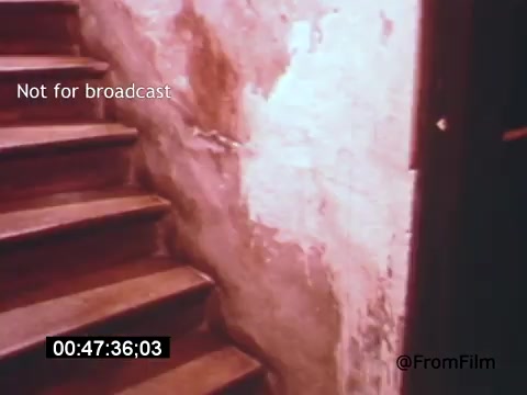 The still from 'Vincent Van Gogh: A Self-Portrait' (1961) features a dimly lit stairway with wooden steps leading upwards. The walls are worn and textured, showing peeling paint and rough surfaces, creating a somber, atmospheric setting. The scene captures a sense of introspection, reflective of Van Gogh's troubled life and artistry. The presence of the timecode indicates it’s likely from a specific moment in the film, emphasizing its context within the narrative.