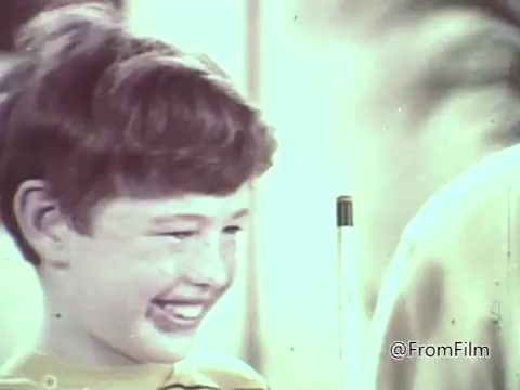 The still from the 1960s M&M's animated commercial features a smiling boy, likely showcasing the playful and cheerful atmosphere typical of candy advertisements of that era. The background hints at a lively setting, consistent with the nostalgic and fun vibe aimed at children. The overall aesthetic reflects the animation style and visual charm of commercials from that decade.