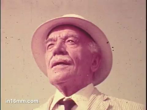 The still features an elderly man wearing a straw hat and a light-colored striped suit. He gazes upward, suggesting a sense of contemplation or hope. The background is minimal, focusing attention on his expression and attire, capturing the essence of the 1975 PSA aimed at promoting awareness for senior citizens.