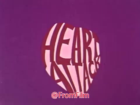The still from the 1969 Blue Cross animated PSA features bold, stylized text reading 'HEART ATTACK,' set against a vibrant purple background. The design mimics the shape of a heart, emphasizing the health theme of the message. The animation style is characteristic of the era, combining strong visual elements with a focus on raising awareness about heart health issues, specifically heart attacks and angina.