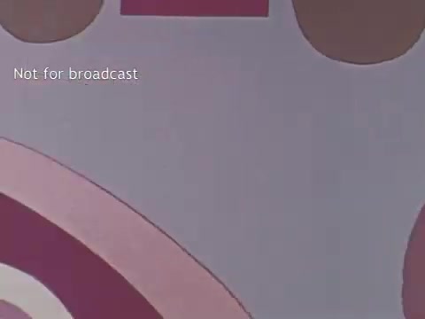 The still from the 1970s US Dairy Council PSA features a colorful, abstract background with various circular shapes in shades of pink and brown. The text 'Not for broadcast' is displayed, indicating that this image is not intended for public airing. Overall, the visual aesthetic reflects the playful design style typical of the era, potentially aimed at engaging viewers about dairy products and their benefits.