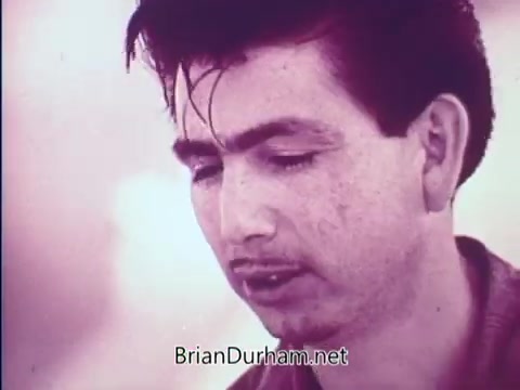 The still features a young man with a serious expression, looking downward. His hair is styled with a slight wave, and he appears to be engaged in thoughtful reflection. The image has a soft color palette, likely indicative of the era, and conveys a mood of introspection or concern. The context suggests themes of societal change or progress discussed in the 1968 PSA.