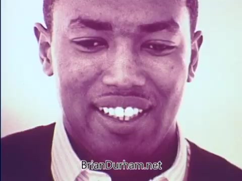The still from the 1968 PSA 'Plans for Progress: Things Are Changing' features a young man smiling, highlighting positive change and optimism. The image captures a moment of personal expression, aligning with the themes of progress and hope during a transformative era. The warm tones contribute to the uplifting mood of the scene.