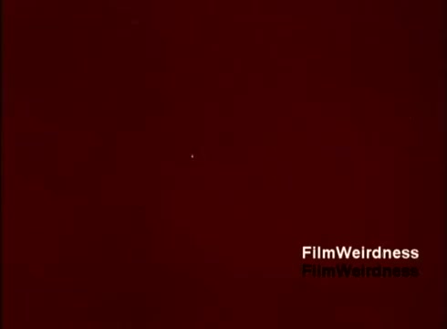 The still from 'Bell System Film from the 1970s' captures a moment of low visibility against a reddish backdrop. There is a faint, small white dot, which might suggest a focus point in the film, perhaps highlighting a detail related to telephone manufacturing or technology. This image seems to evoke a sense of nostalgia, representing a period of innovation within the Bell System. The lack of beginning or ending titles adds to its enigmatic quality.