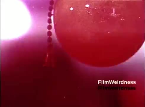 The still from the 16mm film 'Bell Performance' features a visually striking image with a prominent red hue. It appears to showcase abstract shapes, possibly representing telephone components or production elements. The focus seems to be on the aesthetics of filmmaking, highlighting a nostalgic glimpse into the Bell System era through its intriguing visuals. The lack of titles adds a mysterious quality, enhancing its appeal for fans of vintage telecommunications history.