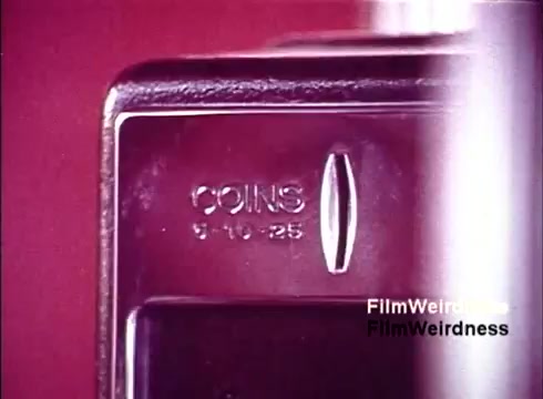 The still from 'Bell System Film' features a close-up of a payphone coin slot, prominently displaying the inscription 'COINS 5-10-25.' The image captures a nostalgic moment from the 1970s, evoking memories of telephone use before the advent of mobile devices. The film's focus on the mechanics of telephone technology reflects the era's fascination with telecommunications, showcasing a pivotal point in communication history.