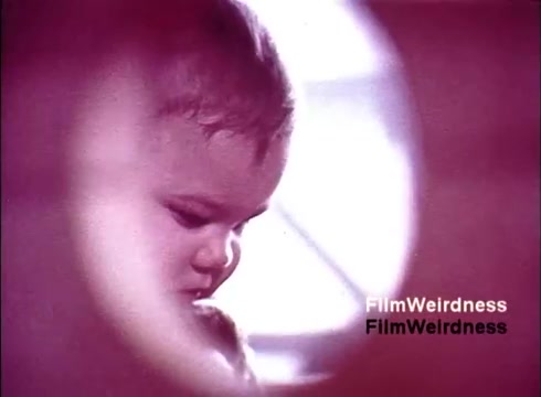 The still from 'Bell Performance' features a close-up of a child's face, captured with a circular frame that adds a unique perspective. The soft focus and warm tones evoke a nostalgic feel, possibly connecting the innocence of childhood with the reliability of telecommunications. The imagery suggests a contrast between human connection and technological advancement, typical of Bell System nostalgia from that era.