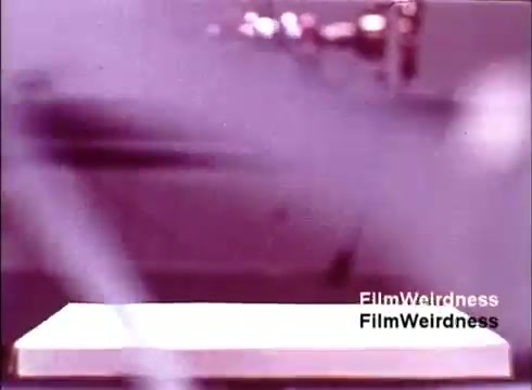 The still from 'Bell Performance' features a close-up view of telephones being created, likely showcasing the manufacturing process. The film, capturing Bell System nostalgia, reflects on the era of telecommunications in the 1970s, emphasizing the craftsmanship and technology involved in producing these iconic devices. The soft focus and color palette give it a vintage feel, celebrating the heritage of the Bell System.