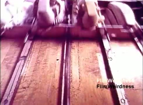 The still from 'Bell System Film from the 1970s' showcases a close-up view of machinery involved in the production of telephones. The equipment, featuring gears and metallic components, operates on tracks, emphasizing the industrial process of manufacturing. The vivid colors and focus on mechanical details evoke a sense of nostalgia for the era of telecommunications development, capturing the intricate work behind the creation of everyday technology.