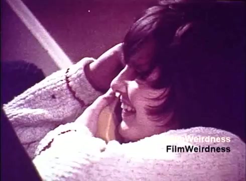 The still from the 'Bell System Film from the 1970s' features a young person smiling while talking on a telephone. The warm color palette and nostalgic aesthetic evoke a sense of familiarity and warmth associated with personal communication. The film captures the enthusiasm and connection of the era, likely showcasing the joy of using telephones amidst the background of their production and innovation.