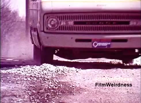 The still likely depicts a vehicle, possibly a service truck, driving over a gravel road. Dust is kicked up from the ground, emphasizing movement and perhaps the ruggedness of the terrain. The film, identified as a 1970s piece from Bell System, captures an era of telecommunications with a focus on the processes and challenges of telephone manufacturing and installation. The absence of titles suggests an informal or unedited presentation, giving it a nostalgic feel for those familiar with Bell System's history.