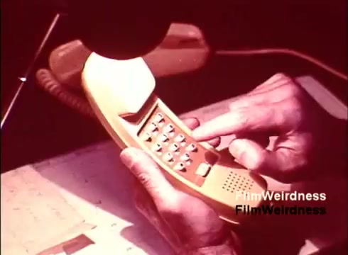 The still features a close-up of hands interacting with a classic telephone, likely from the 1970s, showcasing its design and functionality. The phone is yellow and has a keypad, emphasizing the technology of that era. The film captures the essence of Bell System nostalgia, highlighting the creation and testing of telephones. The overall tone suggests a focus on performance and engineering within the telecommunications industry.