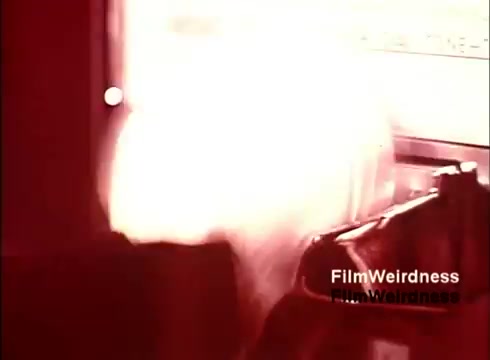 The still from the 16mm film 'Bell Performance' captures an industrial scene related to the creation of telephones. The image likely displays machinery or equipment in action, producing components essential to telecommunications, evoking a sense of nostalgia for Bell System's history. The color and lighting suggest a vintage aesthetic typical of 1970s film, emphasizing the manufacturing process.