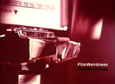 The 16mm still from 'Bell Performance' captures a close-up of a payphone's coin slot and receiver, likely highlighting the technological aspects of telecommunications from the 1970s. The warm, sepia-toned colors evoke a sense of nostalgia, connecting viewers to the era when these phones were common. The film seems to explore the manufacturing and operational processes behind telephones, reflecting on the history and impact of the Bell System. The absence of titles adds to its documentary feel, emphasizing the raw, unfiltered glimpse into this slice of technological history.