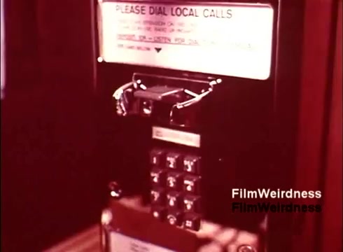 The still from 'Bell System Film from the 1970s' features a close-up of a payphone, highlighting its keypad and instructions for dialing local calls. The design reflects the era's technology, showcasing the functional and straightforward aesthetic of telephone communication at the time. The film evokes nostalgia for the Bell System and offers a glimpse into the past methods of telecommunication.