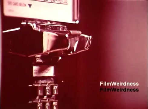 The still showcases a close-up view of a vintage payphone, likely from the 1970s Bell System. The focus is on the coin slot and the keypad, highlighting the design of telecommunication technology from that era. The muted colors and retro aesthetic evoke nostalgia for a time when such devices were commonplace in public spaces. The presence of the text 'FilmWeirdness' suggests it is part of a broader collection or commentary on vintage media.