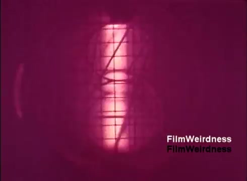 The still captures a moment from 'Bell Performance,' showcasing a close-up of a manufacturing process, possibly related to the creation of telephone components. The imagery is characterized by a pinkish hue, suggesting a focus on the machinery at work, reflecting the technical aspects of telecommunications during the 1970s. The absence of titles hints at a raw and unpolished presentation, emphasizing the nostalgic feel of vintage telecom technology.