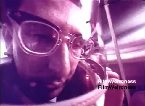 The still from 'Bell Performance' showcases a close-up of a man wearing large round glasses, deeply focused on a telephone apparatus. The film captures a nostalgic glimpse into the 1970s Bell System, possibly highlighting the manufacturing process of telephones. The imagery suggests a blend of human interaction with technology, reflecting the era’s innovations in telecommunications. The color tone indicates a vintage aesthetic, enhancing the nostalgic feel.