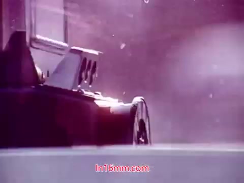 The still from 'Performance' (1971) shows a close-up of a vintage film projector, partially obscured by a pinkish hue. The projector appears to be winding film, capturing the essence of analog cinema. In the context of the end titles, it likely presents the production details, including the date and the cast and crew, reflecting a nostalgic homage to the film's creation.