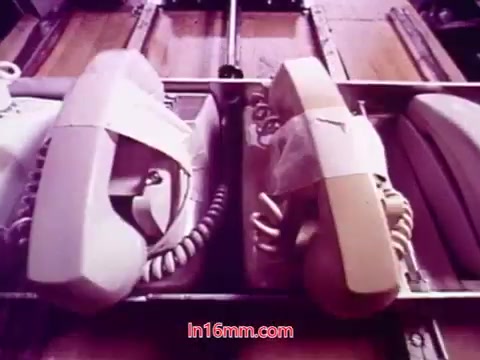 The still from 'Performance' features a close-up view of two retro telephones, one white and one beige, positioned on a flat surface. They are partially obscured by tape, suggesting a presentation or art installation. The print has a vintage aesthetic typical of 16mm film, with soft, muted colors. This moment captures an intriguing juxtaposition of technology and art, reinforcing the film’s thematic connections. The end titles provide production details, highlighting the film's significance and the contributions of its cast and crew.