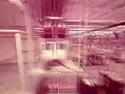 The 16mm still from 'Performance' — a Bell System Film from 1971 — showcases an industrial setting, possibly a factory or assembly line. It features a pinkish tint, suggesting a unique aesthetic. Equipment and machinery are prominent, creating a sense of motion and operation. The end titles indicate the date of production, along with details about the cast and crew involved, marking its completion. This still encapsulates the film's industrial theme and provides context for its historical significance.