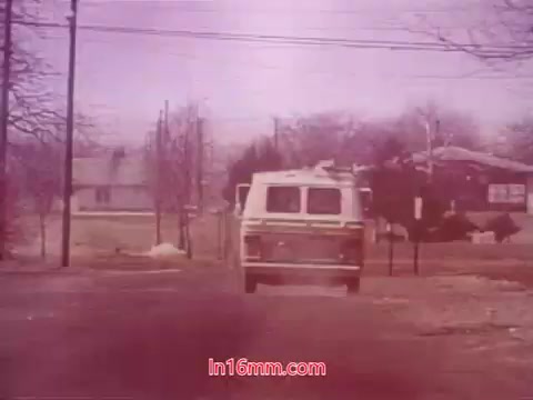 The still from the 16mm film 'Performance' (1971) features a white van driving down a rural street, surrounded by leafless trees and houses in the background. The image conveys a quiet, possibly nostalgic atmosphere, typical of the film’s themes. The end titles suggest a sense of closure, listing the date of production and details of the cast and crew involved. The vintage quality of the print adds to its documentary feel.