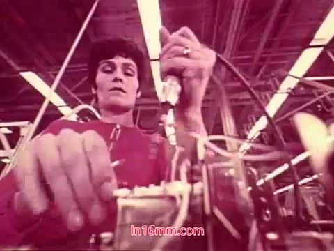 The still from the 16mm film 'Performance' (1971) features a technician working on machinery in a manufacturing setting. The focus is on their hands as they manipulate equipment, reflecting a labor-intensive environment. The color palette suggests a vintage aesthetic, typical of films from that era, enhancing the industrial theme. This scene likely emphasizes the intricacies of technical work and the human element in production processes. The end titles you mentioned would provide insights into the film's production details, cast, and crew.