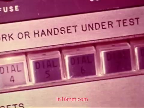 The still from the 16mm film 'Performance' features a close-up of a telecommunications testing device. The panel displays various buttons and dials labeled 'DIAL 4,' 'DIAL 5,' and 'DIAL 6,' alongside a message indicating that the 'MARK OR HANDSET UNDER TEST.' The image is rich in color and reflects the technology of the early 1970s, likely emphasizing the film's theme related to communication systems or testing protocols. This still serves as a visual record from the end titles of the film, providing insight into its production context.