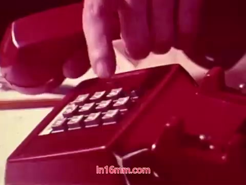The 16mm still from 'Performance' features a close-up of a hand pressing buttons on a vintage red telephone. The emphasis is on the phone's keypad, capturing the era's design. The image is likely vibrant, showcasing the film's production style from 1971. This particular still serves as a concluding moment, referencing the film's credits, which include the production date and the cast and crew involved.