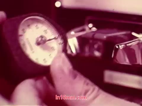 The still from the 16mm film 'Performance' (1971) depicts a close-up of a hand holding a gauge or dial, likely a pressure meter or similar instrument. The background features a mechanical device, possibly part of a Bell System equipment setup. The visual emphasizes a tactile interaction with technology, reflecting the film's exploration of themes related to systems and performance. The end titles convey the production date and credits for the cast and crew.