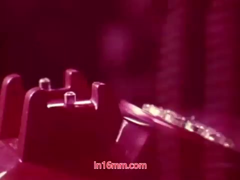 The still from the 16mm film 'Performance' shows a close-up shot of a rotary phone. The colors are rich, likely with a pinkish tint. The image likely captures the film's aesthetic, which blends a sense of nostalgia with a focus on the technology of the time. As it features the end titles, it provides context about production and the cast and crew involved, marking the conclusion of the film.