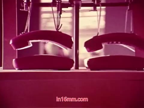 The 16mm still from 'Performance' - Bell System Film (1971) features two vintage rotary telephones, prominently displayed. The colors are warm, with reddish hues, lending a nostalgic feel. This shot likely represents a key thematic element related to communication, reflecting the film's exploration of technology and its impact on society. The end titles provide production details, including the date and cast and crew credits. The overall composition emphasizes the era's aesthetics and thematic concerns.