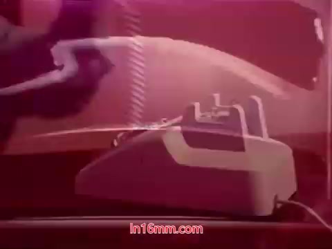 The still from 'Performance,' a 1971 Bell System Film, showcases a close-up of a rotary telephone on a glossy surface, with a soft light casting a warm tone over the scene. The background is slightly blurred, emphasizing the telephone's details. End titles are present, providing production date and credits for the cast and crew. The overall aesthetic evokes a nostalgic, retro vibe.