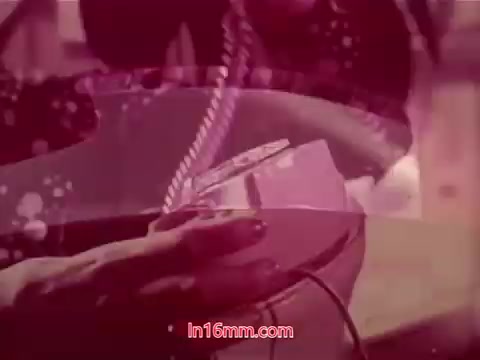 The still from the 16mm film 'Performance' (1971) features a close-up of a hand interacting with a device, possibly a telephone, set against a backdrop of vibrant colors and abstract patterns. The image suggests a blend of personal engagement and technology, with a softly blurred focus. The end titles likely provide production details, including the date and credits for the cast and crew, encapsulating the film's context. The aesthetic reflects the era's artistic style, emphasizing a mix of modernity and intimacy.