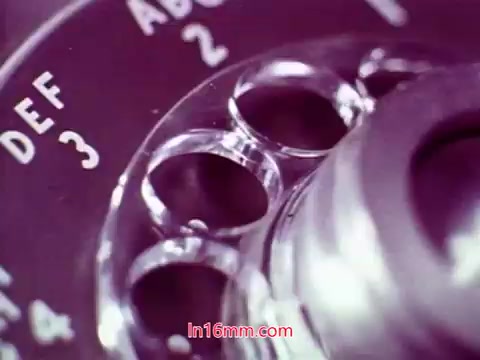 The still from the 16mm film 'Performance' features a close-up of a rotary phone dial. The focus is on the dial's numbered holes and letters, highlighting its vintage design. The colors may reflect the film's era, with a slight grain indicative of 16mm prints. This ending section includes production details, such as the date and credits for the cast and crew, serving as the film's conclusion.