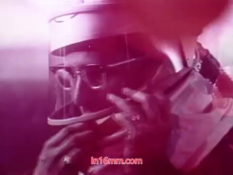 The still from the film 'Performance' features a close-up of a person wearing a protective helmet and mask, suggesting a high-tech or scientific context. The soft, muted colors create a dreamlike atmosphere, highlighting the character’s focused expression. The image likely conveys themes of exploration or advanced technology, tying into the film's broader narrative. The end titles provide key production information, including dates and cast, concluding the film with a sense of completeness.