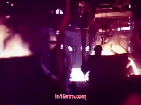 The still from 'Performance' - Bell System Film (1971) showcases a dramatic industrial setting. The scene features workers engaged in a molten metal pouring process, surrounded by glowing furnaces and machinery. The color palette likely emphasizes the heat and intensity of the environment. This particular moment, possibly the end titles, includes production details and credits for the cast and crew, capturing the artistic essence of the film.