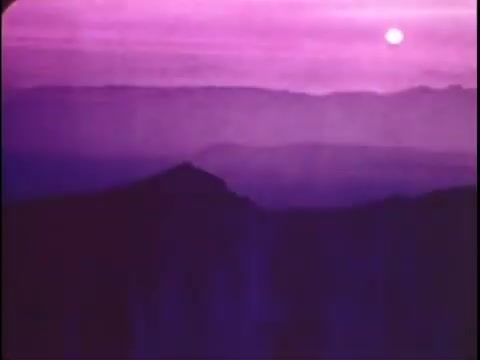 The still from the Sikorsky S-76 promo film features a striking landscape at dusk, dominated by purple and pink hues in the sky as the sun sets. The foreground showcases a silhouette of mountains, creating a dramatic contrast against the vibrant background, which conveys a sense of tranquility and beauty. This moody imagery sets an atmospheric tone, likely intended to evoke feelings of innovation and adventure associated with the Sikorsky S-76.