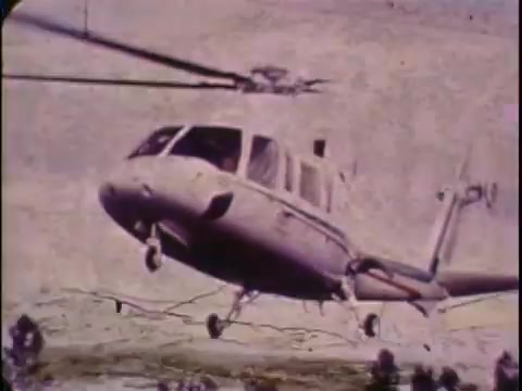 The still from the 16mm promo film for the Sikorsky S-76 features a helicopter in flight, showcasing its sleek design. The background appears to be a rugged terrain, enhancing the sense of motion and capability of the aircraft. The color is slightly muted, typical of the era's filming style. This brief moment encapsulates the essence of 1970s aviation promotion, highlighting the Sikorsky S-76’s innovative features and performance in a visually striking manner.