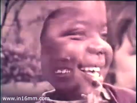 The still from the 1968 PSA 'Head Start' features a close-up of a smiling child, radiating joy and innocence. The image has a vintage aesthetic characteristic of 16mm film, with a slightly blurred effect that adds to its charm. The context highlights the Head Start program, emphasizing early childhood education and development initiatives in a heartfelt and engaging manner, complemented by the presence of Lady Bird Johnson as a key advocate.