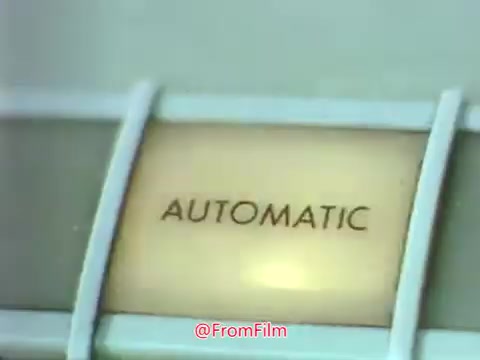The still features a close-up of a terminal labeled 'AUTOMATIC,' highlighting the technology of the era. This image connects to the context of the Point Park College PSA from 1969, showcasing the school's embrace of emerging technology like punched cards and hard copy terminals, reflective of the educational advancements at that time.