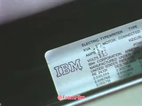 The still features a close-up of an IBM electric typewriter, showcasing its technical specifications. It highlights the type and model information, along with electrical requirements such as voltage and amperage. The context points to Point Park College's late 1960s era, emphasizing the technology used during that time for communication and education. The use of punched cards indicates an early form of data processing, reflective of the technological landscape of the period.