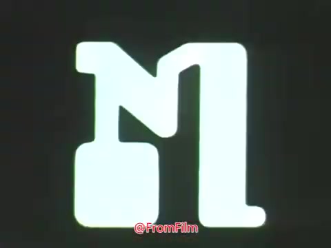 The still features a stylized logo that appears to depict a large letter 'M' intertwined with another character, likely referencing a broadcasting or media context. This design aligns with the visual themes of the era, emphasizing simplicity and boldness in graphic design. The overall aesthetic suggests a focus on innovation and technology, which resonates with the PSA's themes from Point Park College in 1969, showcasing its progression in education and media.